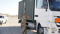 Ein Soldat steht an einem Lastkraftwagen und spricht mit dem Fahrer