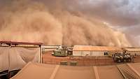 Eine große Sandsturmwolke rollt über das Bundeswehr-Camp Castor ein.