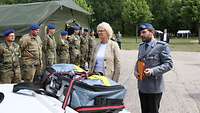 Ein Soldat zeigt Christine Lambrecht Sanitätszubehör neben einer Reihe anderer Soldaten.