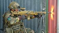Ein Soldat lehnt mit seiner Waffe an einer Häuserwand und schießt.