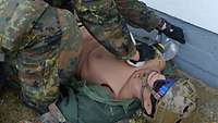 Ein Soldat versorgt eine Sanitätspuppe.
