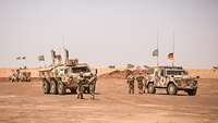 Drei Fahrzeuge vom Typ Enok und Fuchs stehen in Wüstengebiet, daneben stehen Soldaten