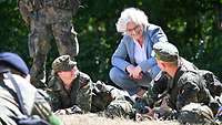 Christine Lambrecht unterhält sich mit zwei Soldaten, die für eine Übung auf dem Boden liegen.