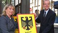 Eine Frau und ein Mann mit Behördenschild des Bundesamtes für Infrastruktur, Umweltschutz und Dienstleistungen der Bundeswehr