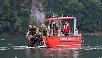 Ein Boot der Feuerwehr mit Helfern nimmt einen im Wasser gelandeten Fallschirmspringer auf.