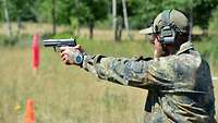 Ein deutscher Soldat schießt im beidhändigen Anschlag mit einer Pistole.