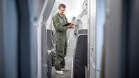 Ein Techniker der Bundeswehr steht im Gang eines Airbus A321LR und macht Notizen auf einem Klemmbrett