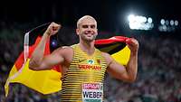 Ein Bundeswehrsportler Julian Weber jubelt mit der Deutschlangflagge in den Händen