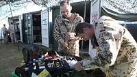 Zwei Soldaten in ABC-Schutzanzügen aus dem Bereich der Kampfmittelbeseitigung überprüfen ihre Ausrüstung.