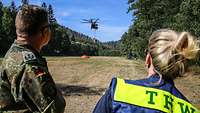 Waldbrand in der Sächsischen Schweiz, ein Soldat und eine Mitarbeiterin vom THW beobachten eine Wasserbetankung eines CH -53
