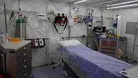 Ein Krankenbett in einem Zelt. Darum herum stehen medizinische Geräte