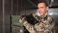 Ein Soldat stapelt grüne Kisten mit Sanitätsmaterial in einen Container