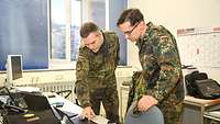 Zwei Soldaten schauen auf einen Computer.