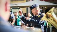 Ein Soldat in Uniform dirigiert Musiker