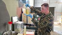 Ein Soldat hält eine Glasflasche mit Kraftstoff in die Luft und schaut, ob Schmutz erkennbar ist