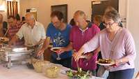 Gäste stehen in der Schlange am Grillbuffet an