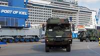 Militärfahrzeuge im Hafengelände, im Hintergrund ein Kreuzfahrtschiff