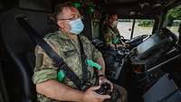 Ein Soldat sitzt mit einem Controller in der Hand auf dem Beifahrersitz in einer Lkw-Fahrerkabine.
