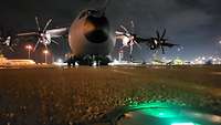 Ein A400M steht bei Nacht auf dem Flugfeld in Singapur