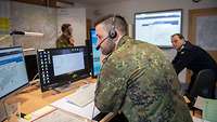 Soldaten arbeiten in einem Lagezentrum schauen auf Monitore und telefonieren