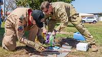 Zwei Soldaten versuchen mit alternativen Hilfsmitteln ein Feuer zu machen