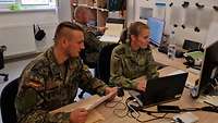 Zwei Soldaten und eine Soldatin arbeiten in einem Büro 