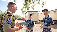 A German soldier talking with two Australian soldiers.