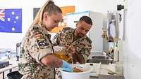 Zwei Soldaten bereiten einen Wurstsalat zu 