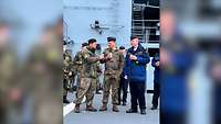 Drei Soldaten der Bundeswehr stehen auf einem Schiff der deutschen Marine gesellig beisammen.