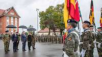 Staatsgäste unter Regenschirmen vor der Front der Ehrenformation mit den Flaggen der Rahmennationen stehend