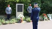 Zwei Soldaten stehen neben einem Gedenkstein. Ein Soldat steht davor.