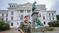 Der Soldat Andre R. steht vor dem Rathaus in Altona. Dort steht eine Reiterstatue von Kaiser Wilhelm I.