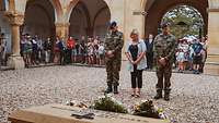 Zwei Soldaten und eine Frau gedenken an einem Grabstein