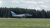 Ein Eurofighter mit Sonderfolierung rollt über die Runway. Im Hintergrund ist ein Wald.