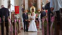 Ein Brautpaar steht in der Kirche vor dem Altar
