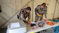 Eine Soldatin und ein Soldat zählen elektronisches Gerät auf einem Tisch