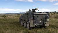 Ein Radpanzerboxer fährt über eine Graslandschaft Richtung Horizont