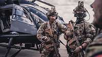 Zwei bewaffnete KSK-Soldaten stehen vor einem Hubschauber.