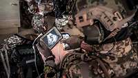 Ein KSK-Soldat bedient ein mobiles Gerät während der Versorgung eines verwundeten Soldaten.