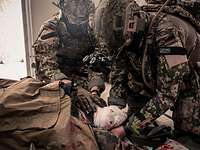 Zwei KSK-Soldaten verbinden den Beinstumpf eines verwundeten Soldaten.