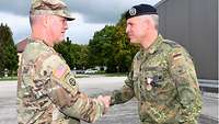 Ein US-amerikanischer General gibt einem deutschen Oberstleutnant die Hand. An seiner Brust hängt ein besonderer Orden.