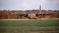 Ein Transportflugzeug vom Typ C-130J Super Hercules landet auf einer Grasfläche.
