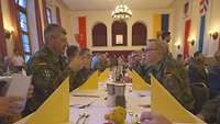 Soldaten sitzen in einem großen Saal an einer langen Tafel zum Abendessen