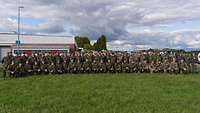 Gruppenfoto mit zirka 80 Soldatinnen und Soldaten auf einer grünen Wiese