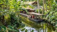 Ein Boot mit Besuchern auf einem künstlichen Fluss im Tropenhaus Gondwanaland.