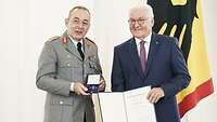 Generalleutnant Breuer mit Bundesverdienstkreuz und Bundespräsident Steinmeier mit Urkunde stehen nebeneinander.