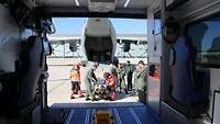 Aus einem Krankenwagen sieht man die geöffnete Heckklappe eines A400M, wo vor Soldaten und Sanitäter um eine Liege stehen.