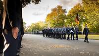 Auf der linken Seite Soldaten und eine Ehrenformation mit Deutscher Flagge marschiert vor diesen.