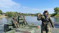 Soldaten überqueren auf einer Schwimmschnellbrücke einen Fluß