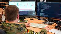 Ein Soldat sitzt am Computer und programmiert.